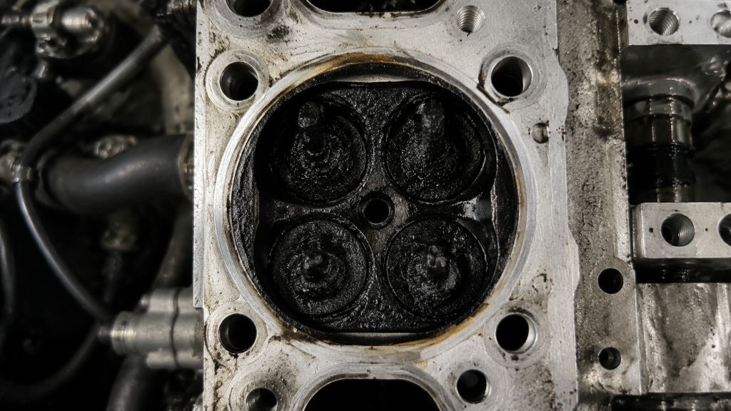 BMW N55 intake valves heavily coated in thick carbon buildup inside cylinder head causing airflow restriction and Check Engine light issues